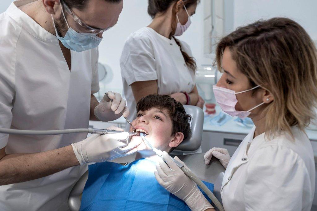 team of dentists treating a young boy for orthodontics in the dentist s clinic
